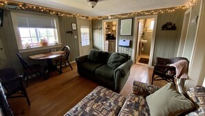 A cozy living room with a sofa, a patterned rug, and a dining area with a table and chairs.