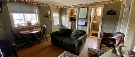Un salon chaleureux avec un canapé, un tapis à motifs et un coin repas comprenant une table et des chaises.
