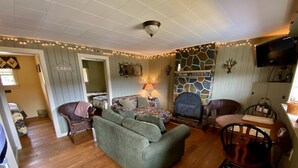 A cabin interior with a sofa, chairs, a fireplace, and a dining table.