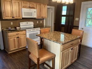 A kitchen with wooden cabinets, a white stove, a microwave, granite countertops, and a bar stool. - Newly renovated farmhouse with a view of Elk Mountain (Pleasant Mount)