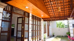 A covered outdoor area with wooden beams and a tiled ceiling, featuring a potted plant and a small garden. - Tenasi Beach Resort (Ahangama)