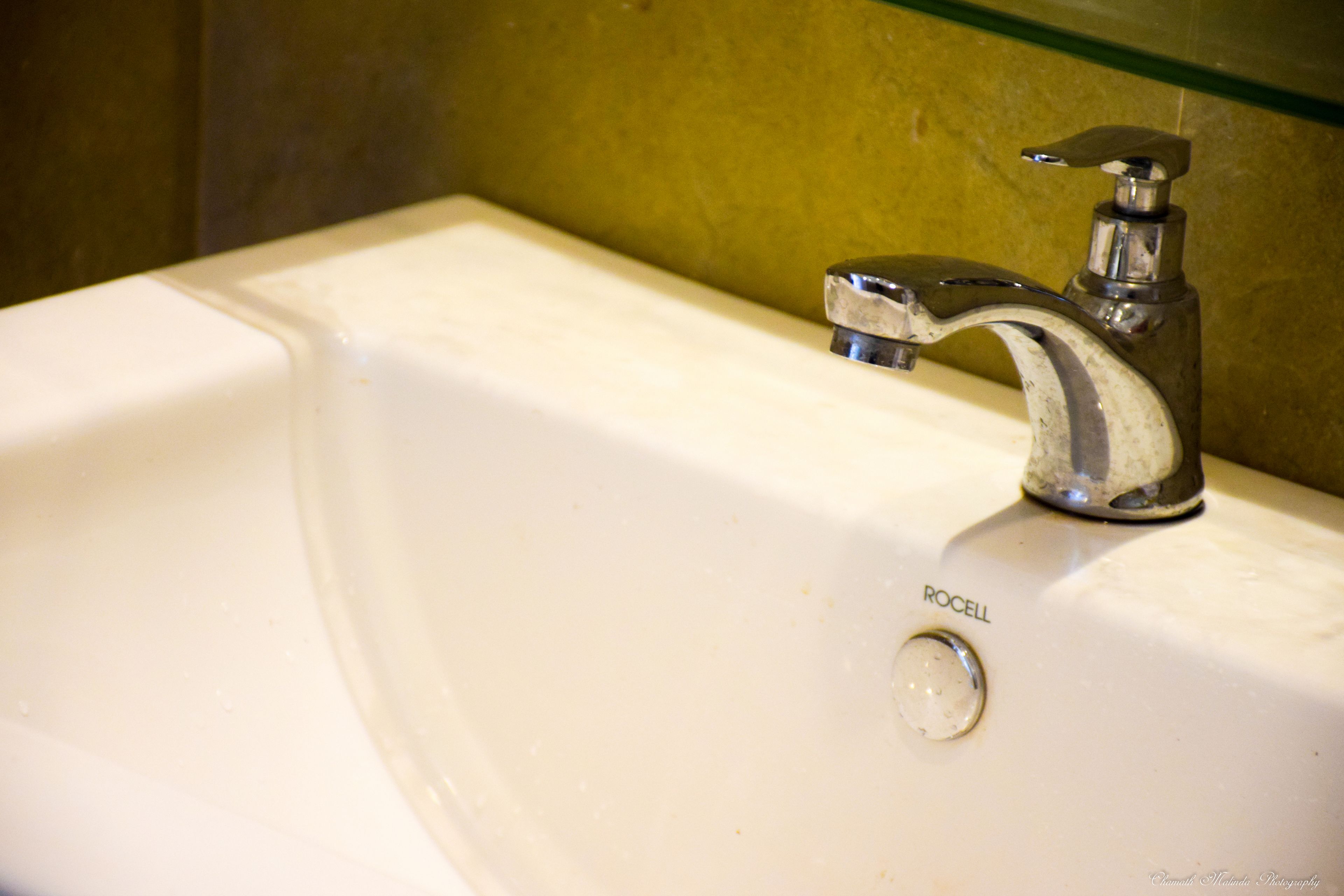 A bathroom sink with a chrome faucet and a visible brand name "ROCELL".