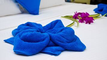A neatly made bed with blue towels and purple flowers.