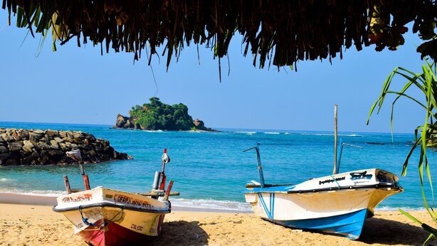 Two boats on a sandy beach with a clear view of the ocean and a small island in the distance. - Tenasi Beach Resort (Ahangama)