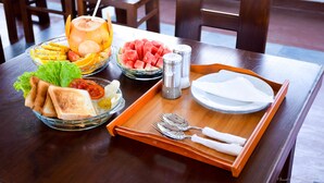 A dining table with a fruit bowl, a tray with cutlery, and a plate. - Tenasi Beach Resort (Ahangama)