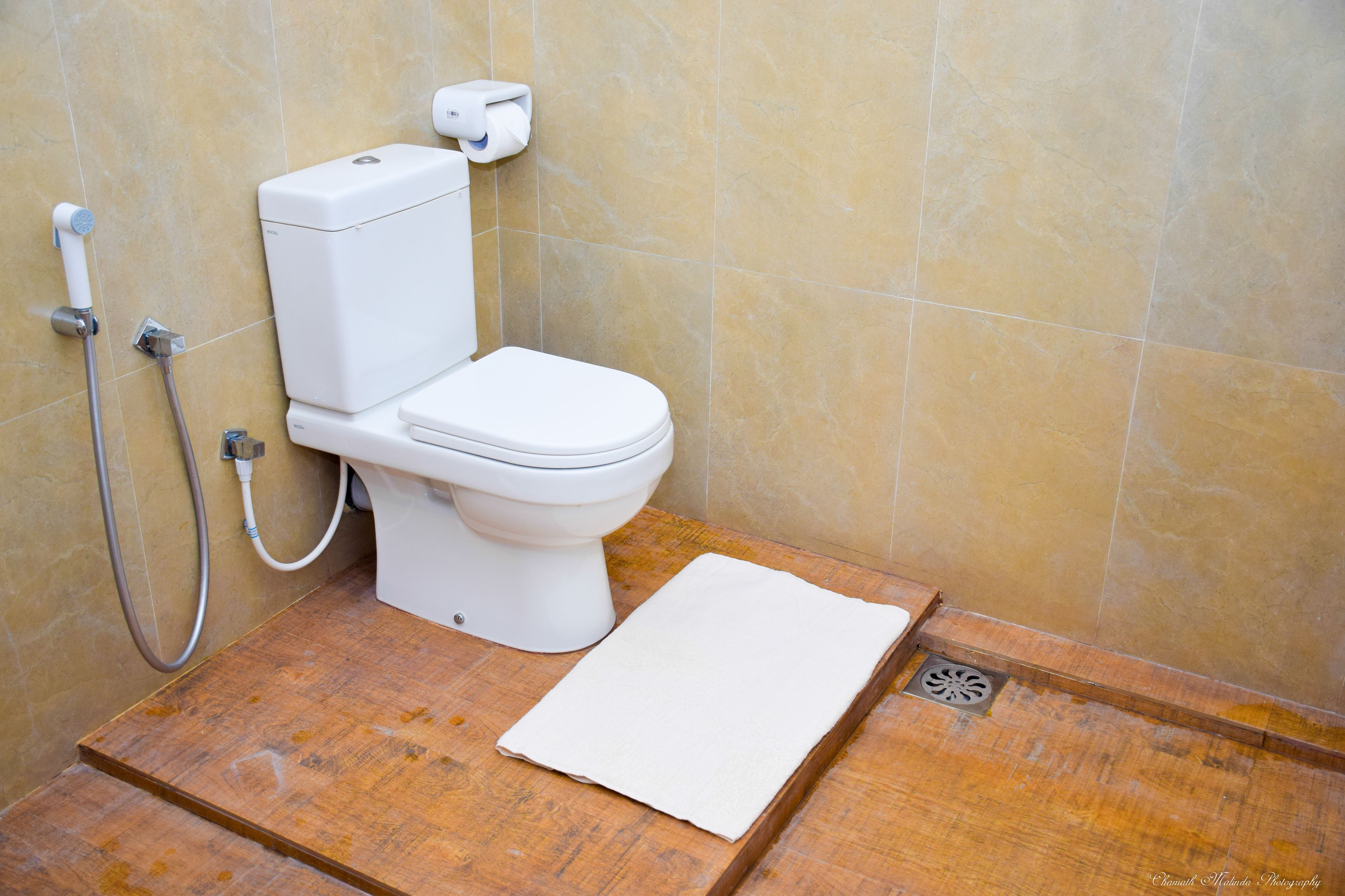 A bathroom with a toilet, a shower, and a wooden floor.