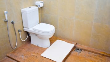 A bathroom with a toilet, a shower, and a wooden floor.