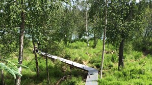 Een houten brug over een grasveld met een looppad van metalen spijlen.