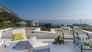 A rooftop terrace with white lounge chairs, a striped towel, and a table with lemons and glasses. - Villa Zvizdan - authentic local experience (Makarska)