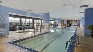 Une piscine intérieure avec des couloirs clairement délimités, un poste de surveillance pour les sauveteurs et des chaises longues.