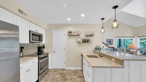 A modern kitchen with white cabinetry, stainless steel appliances, and a hexagonal patterned floor. - Family Friendly Lakeview Upper Vista in Sea Colony West (Bethany Beach)