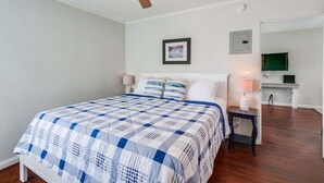 A bedroom with a bed, a ceiling fan, a nightstand, a lamp, a framed picture, and a television on a stand. - 1 Bedroom Condo steps from Ocean and Bay (San Diego)