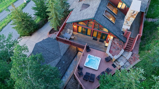 A large, multi-level house with a hot tub, outdoor seating, and a deck.