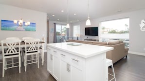 A modern kitchen with white cabinetry, a central island, and pendant lighting.