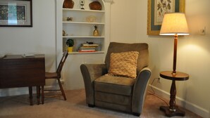 A cozy living room with a brown armchair, a wooden side table with a lamp, a bookshelf with decorative items, and a framed picture on the wall. - Yadkin Valley has the same viticulture stamp as NAPA.  Canoes and Kayaks!! (Elkin)