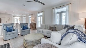 A spacious living room with a high ceiling, a large window, and a ceiling fan. - In Seaside – Nearby Pool & Beach – Emma Lou (Seaside)