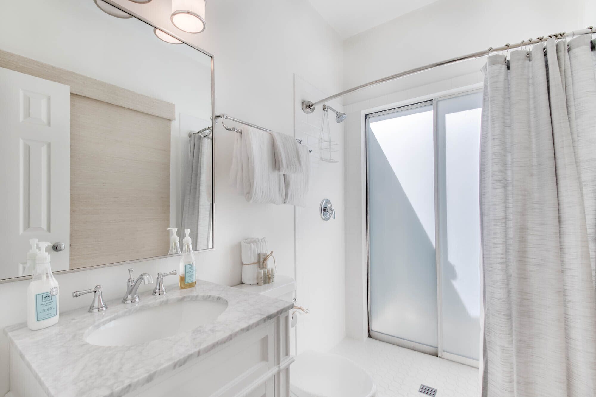 Une salle de bain moderne dotée d’un grand miroir, de deux lavabos, d’une douche et offrant une vue sur l’extérieur.