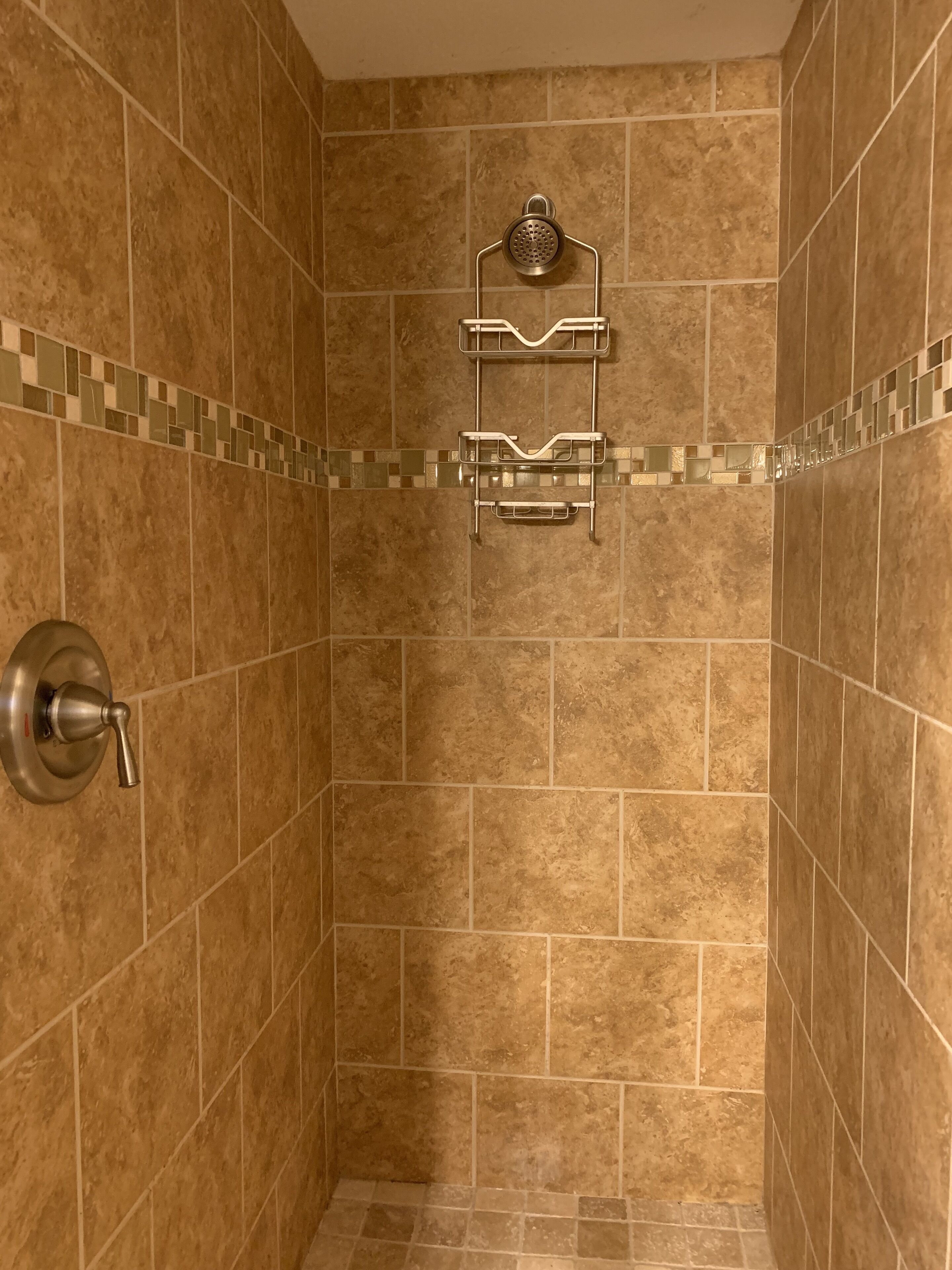 Een douche met een wandmengkraan en douchekop.