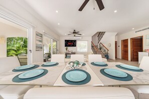 A dining area with a marble table, blue placemats, and white chairs. - Luxury 4BR House + Private Pool + Rooftop Ocean Views + Concierge (Isla Mujeres)