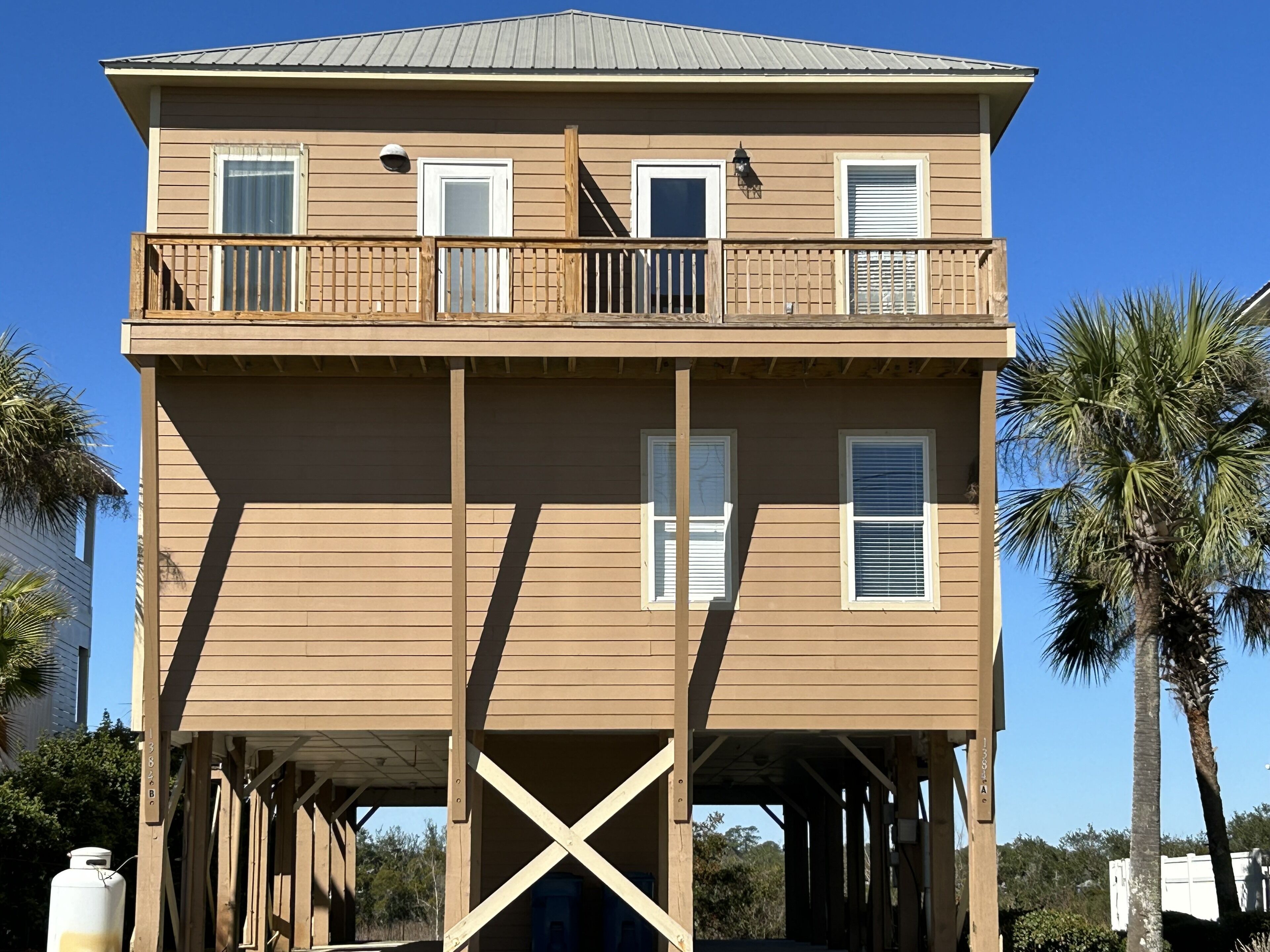 A two-story wooden building with a balcony on the upper floor, supported by wooden stilts.