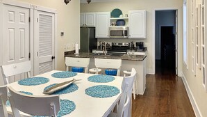 A compact kitchen with white cabinets, a microwave, and a stove. There is a dining table with blue placemats and a fish on it. - Waterfront with 2 Master Suites, Heated Pool, Hot tub. Dock (Gulf Shores)