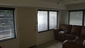 A living room with a brown leather sofa, a ceiling fan, and a door with a window.