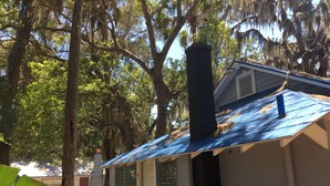 A small house with a blue metal roof, a chimney, and a white door.