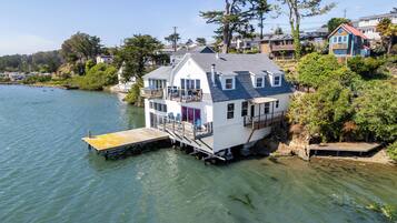 A houseboat with a deck and outdoor seating, docked at a pier.