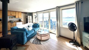Una sala de estar moderna con un sofá, una mesa redonda de centro y vistas al mar a través de amplios ventanales.