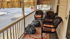 A covered porch with wicker chairs and a stop sign in the background. - Four Blocks To Beach & Boardwalk  + Pet Friendly (Ocean City)