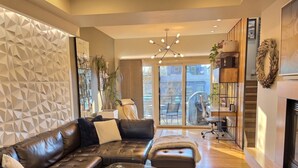 A modern living room with a leather sofa, glass coffee table, and a fireplace. - Rooftop Retreat-modern townhome in the heart of LoHi- roof deck-walk everywhere! (Denver)