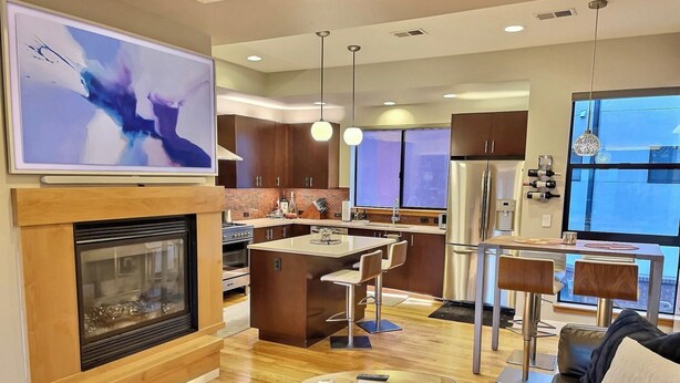 A modern kitchen with a central island, a dining area with a glass table, a leather sofa, and a large abstract painting. - Rooftop Retreat-modern townhome in the heart of LoHi- roof deck-walk everywhere! (Denver)