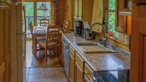 A kitchen with wooden cabinets, a granite countertop, a coffee maker, and a sink. - Trollhaugen—Enjoy Spring and Summer in the Great Smoky Mountains (Sevierville)