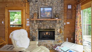 A cozy room with a stone fireplace, a comfortable chair, and a sofa. - Trollhaugen—Enjoy Spring and Summer in the Great Smoky Mountains (Sevierville)