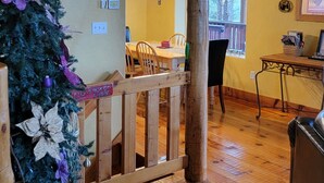 A wooden staircase leading to a dining area with a chandelier, a Christmas tree, and a dining table with chairs.