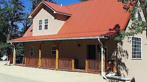 A two-story building with a red roof and a porch with wooden railings.