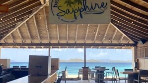 Eine Strandbar namens 'Sapphire' mit Blick auf das Meer und die Berge.