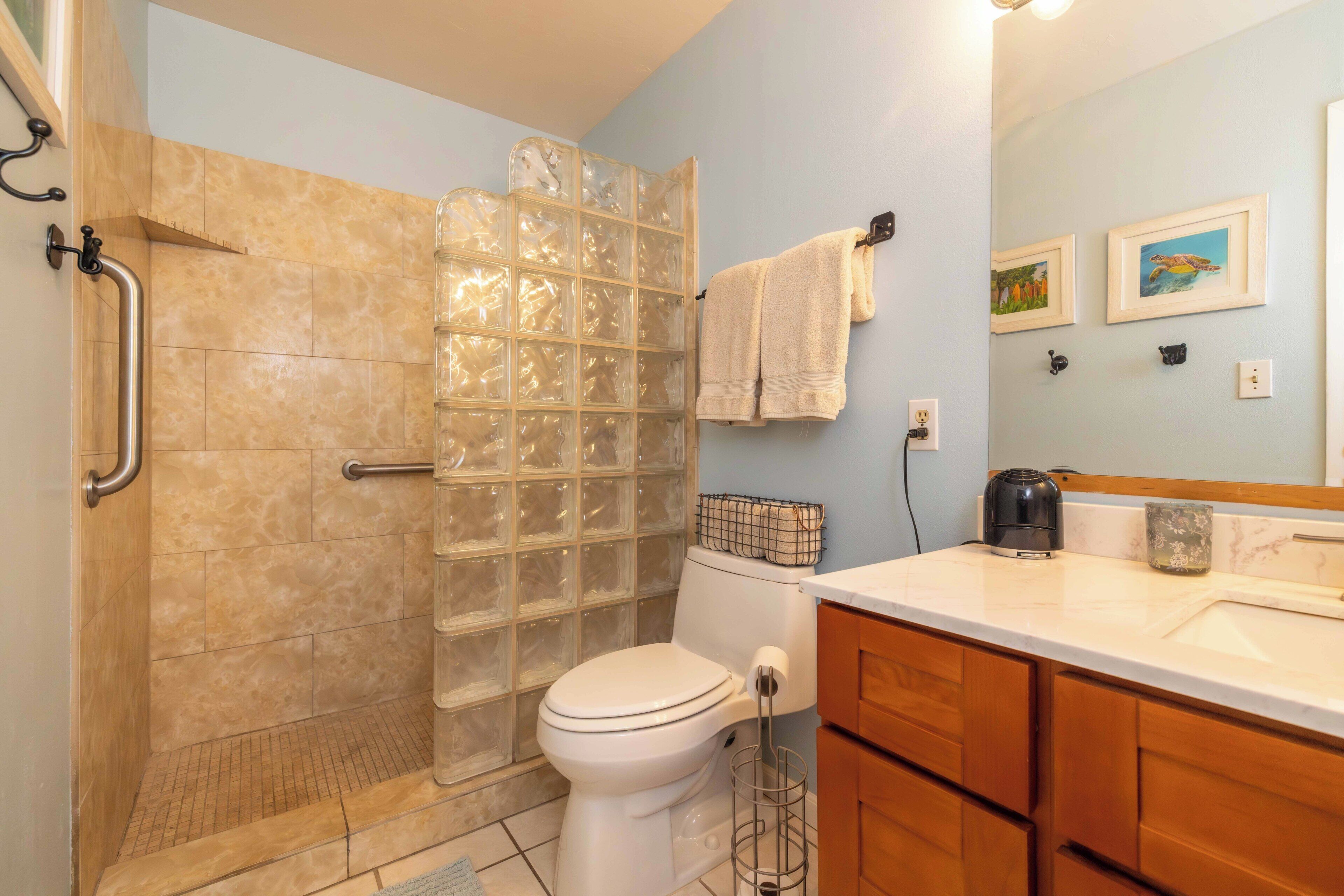 A bathroom with a shower, toilet, sink, and wooden cabinets.