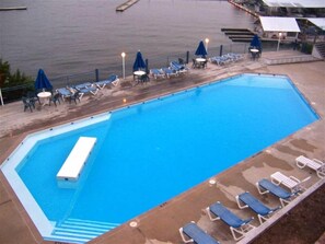 Une piscine rectangulaire dotée d’un plongeoir, entourée de chaises longues et de parasols.