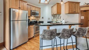 Una cocina moderna con armarios de madera, electrodomésticos de acero inoxidable, una isla central con taburetes altos y un tragaluz.