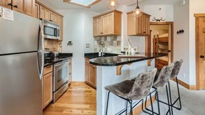 Una cocina moderna con armarios de madera, electrodomésticos de acero inoxidable, una isla central con taburetes y un tragaluz.