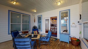 A cozy room with a wooden floor, a dining table with chairs, a fan, and a small table with a board game. - Golf Cart Included, Shared Pool, Pet Friendly, Boardwalk to Beach (Port Aransas)