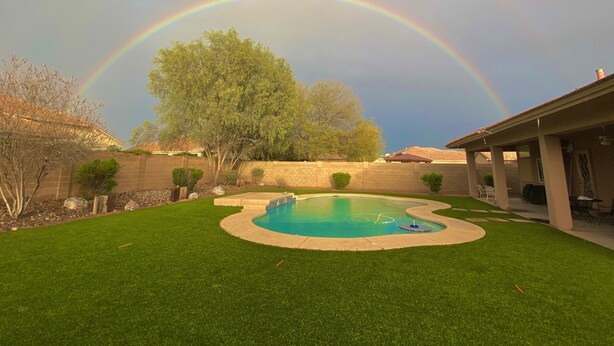 A backyard with a swimming pool, a tree, and a stone wall. - Spacious 4BR Coyote Ranch Retreat with Private Pool & RV Parking in Casa Grande (Casa Grande)