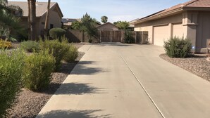 A residential driveway leading to a gated entrance with palm trees and shrubs. - Spacious 4BR Coyote Ranch Retreat with Private Pool & RV Parking in Casa Grande (Casa Grande)