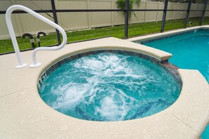 Ein Whirlpool mit einer Tiefenmarkierung von 3 Fuß, umgeben von einem Pool und einer Rasenfläche mit einem Zaun im Hintergrund.