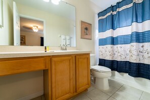 Ein Badezimmer mit einem Holzkosmetikschrank, einer weißen Toilette und einem blau-weißen gestreiften Duschvorhang.