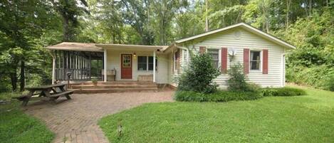 A small, single-story house with a porch and a picnic table in front.