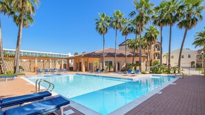 Una piscina con sillones de descanso y palmeras.
