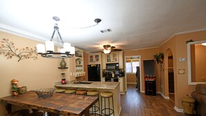 Una cucina con isola centrale, sgabelli da bar, un lampadario e una ventola a soffitto.