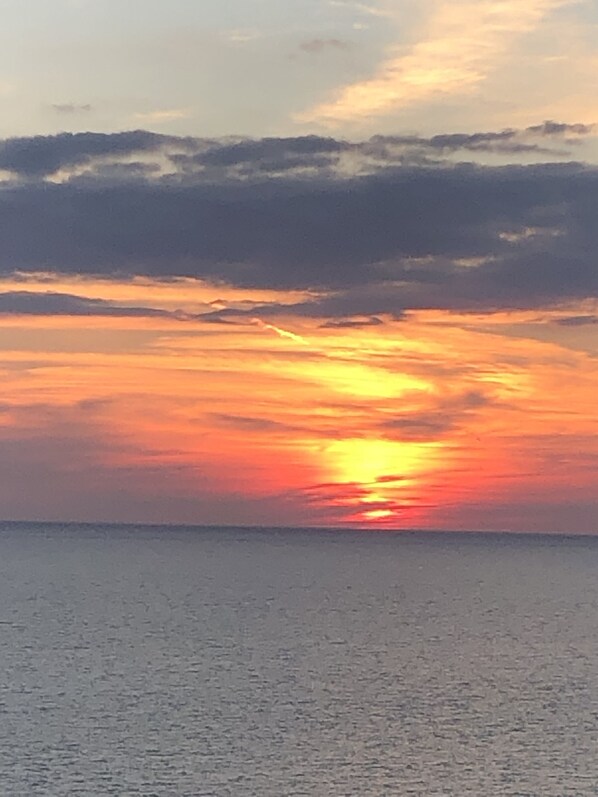 A sunset over a calm sea with a clear horizon.
